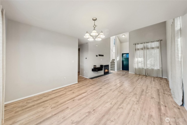 unfurnished living room with light hardwood / wood-style floors and a notable chandelier