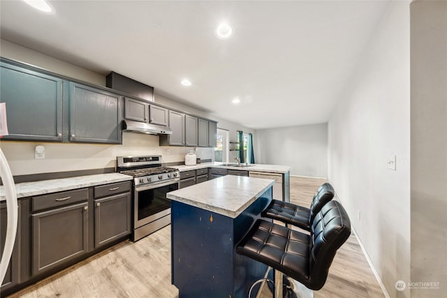 kitchen featuring a center island, stainless steel gas range, light hardwood / wood-style floors, and a breakfast bar