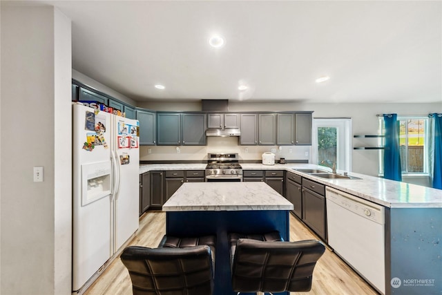 kitchen with a kitchen bar, sink, white appliances, and a center island