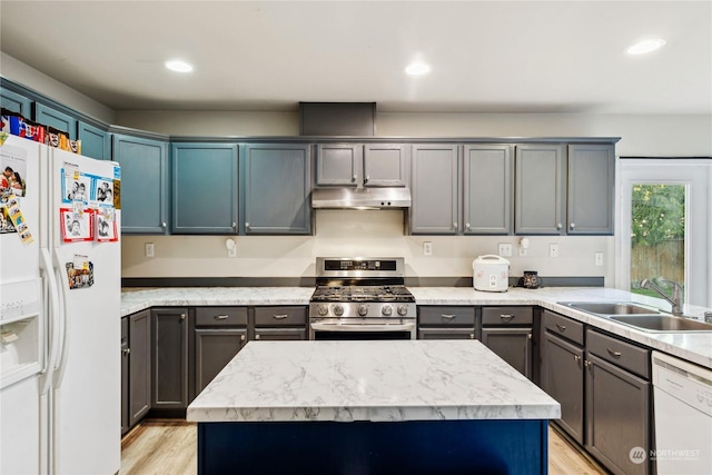 kitchen with sink, a kitchen island, white appliances, and light hardwood / wood-style floors