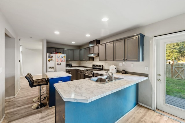 kitchen with a center island, a kitchen bar, appliances with stainless steel finishes, sink, and kitchen peninsula