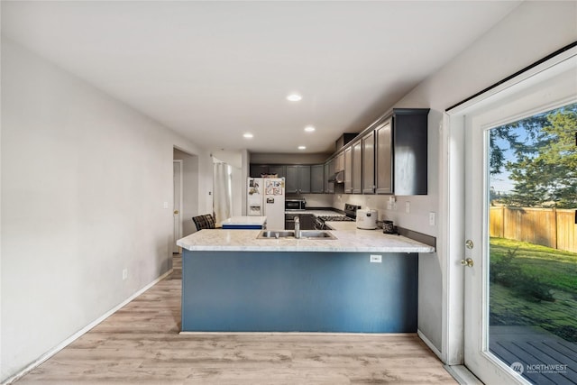 kitchen featuring range, white refrigerator with ice dispenser, sink, light hardwood / wood-style flooring, and kitchen peninsula