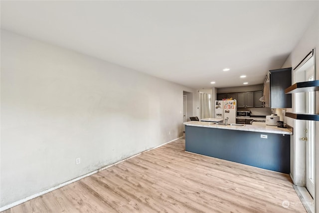 kitchen with sink, light hardwood / wood-style flooring, white refrigerator with ice dispenser, and kitchen peninsula