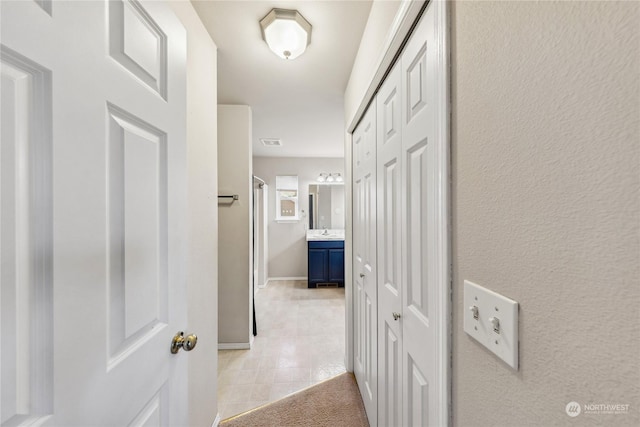 hall featuring sink and light tile patterned floors