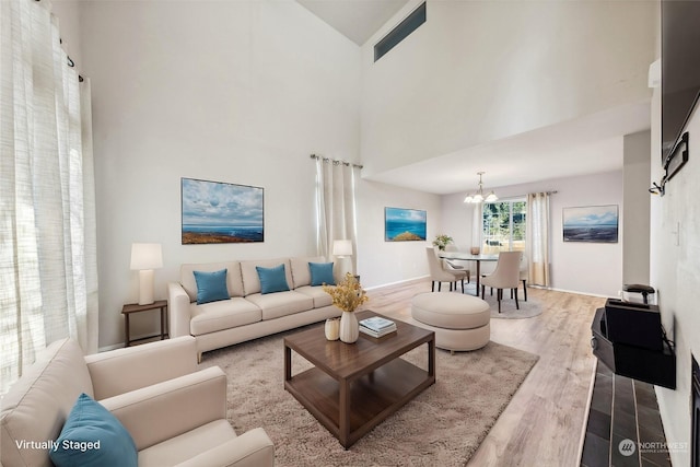 living room with high vaulted ceiling, hardwood / wood-style floors, and a chandelier