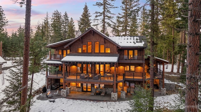 snow covered house with a patio area and a deck