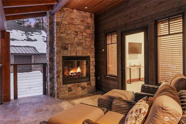 interior space featuring vaulted ceiling with beams, wood ceiling, and an outdoor stone fireplace