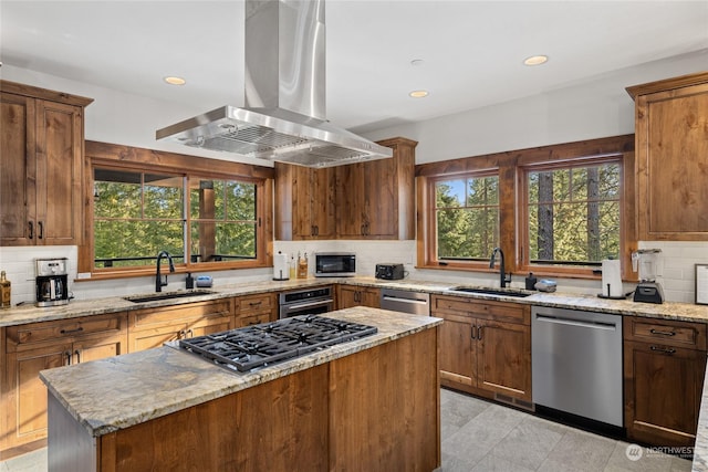 kitchen with stainless steel appliances, light stone countertops, sink, and island range hood