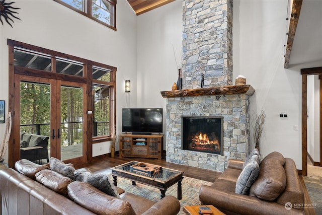 living room with high vaulted ceiling, hardwood / wood-style floors, a fireplace, and french doors