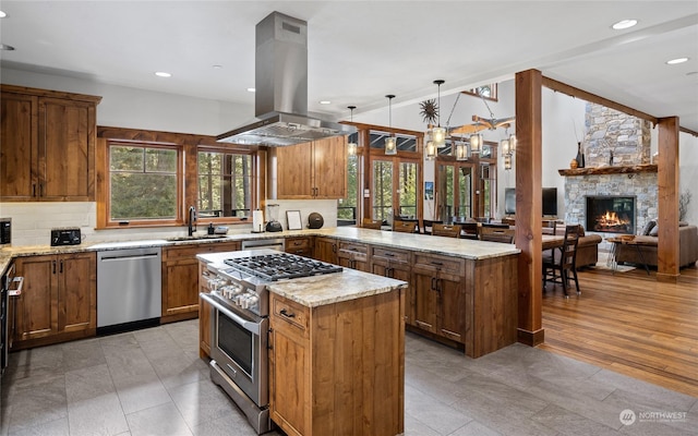 kitchen featuring sink, island range hood, decorative light fixtures, a center island, and appliances with stainless steel finishes