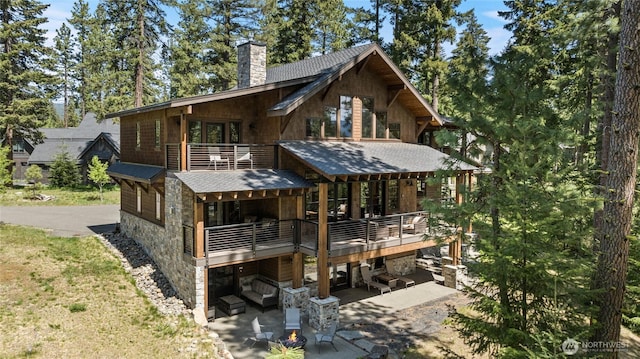 60 Birch Ct, Cle Elum, WA 98922 - back of property with stone siding, a chimney, a balcony, a patio, and a shingled roof