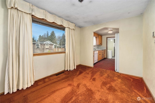 empty room with dark carpet and a textured ceiling