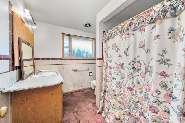 bathroom featuring vanity, toilet, curtained shower, and tile walls