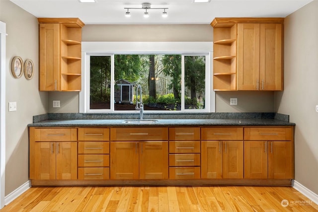 kitchen featuring sink, light hardwood / wood-style flooring, and dark stone countertops