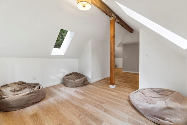 additional living space with wood-type flooring and lofted ceiling with skylight