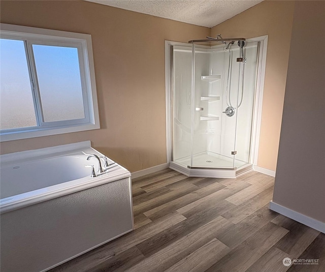 bathroom with plus walk in shower, a textured ceiling, and hardwood / wood-style floors