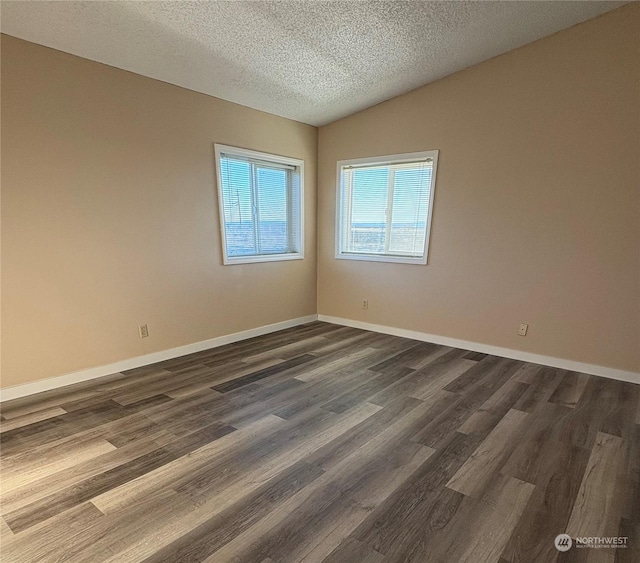 spare room with a textured ceiling, dark hardwood / wood-style flooring, and vaulted ceiling