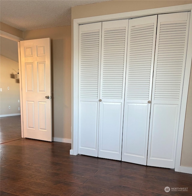 unfurnished bedroom featuring a textured ceiling, dark hardwood / wood-style floors, and a closet