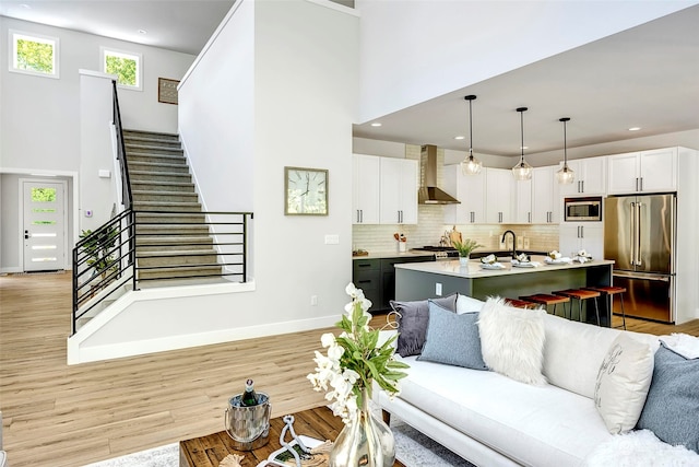 living room with light hardwood / wood-style floors and a towering ceiling