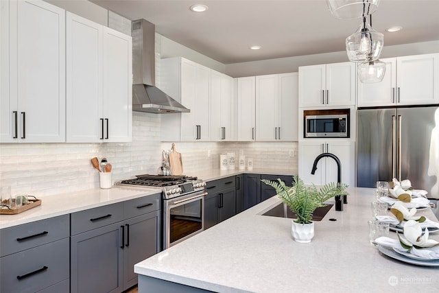 kitchen featuring sink, wall chimney range hood, white cabinets, and stainless steel appliances