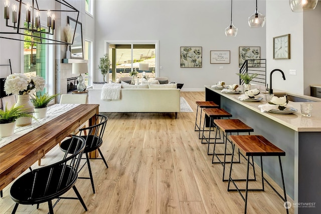 interior space featuring light hardwood / wood-style floors, sink, a tile fireplace, and a towering ceiling