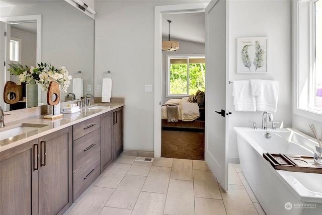 bathroom featuring tile patterned floors, lofted ceiling, a bathtub, and vanity