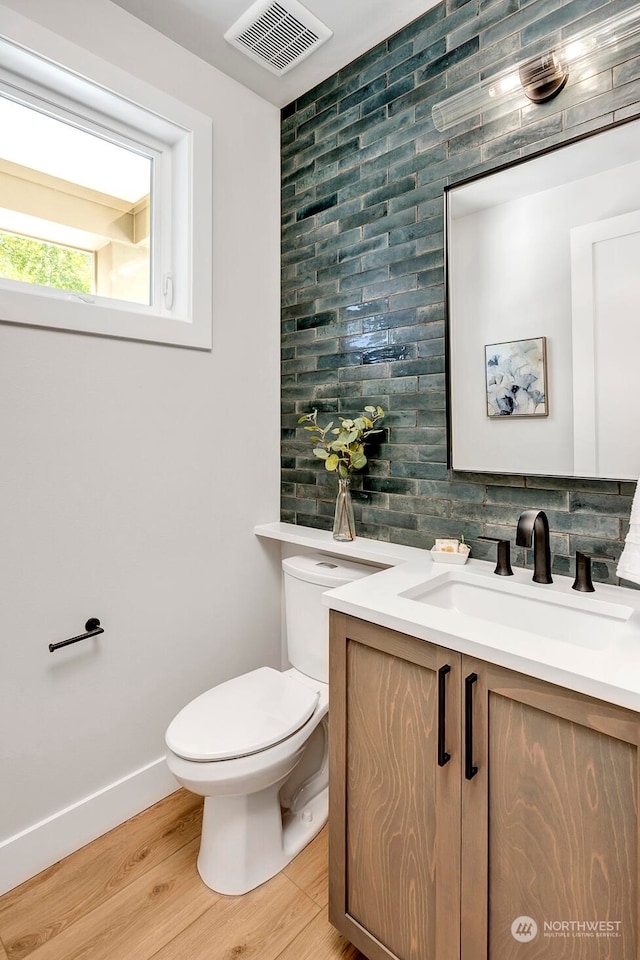 bathroom with toilet, vanity, wood-type flooring, and tasteful backsplash