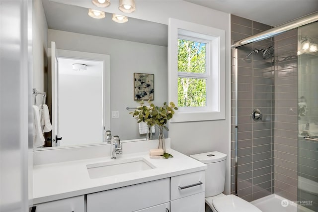 bathroom with toilet, vanity, and a shower with shower door