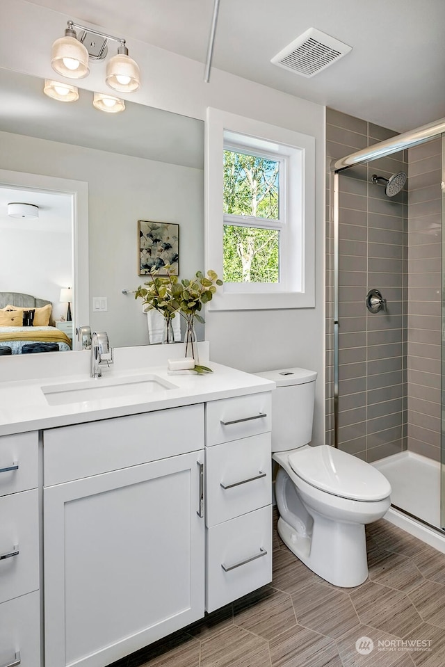 bathroom featuring toilet, an enclosed shower, and vanity