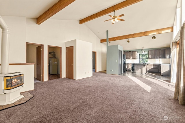 unfurnished living room with ceiling fan, dark carpet, beam ceiling, heating unit, and high vaulted ceiling