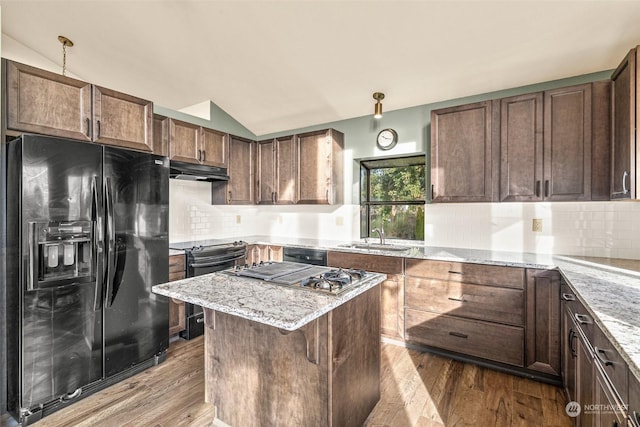 kitchen with decorative backsplash, hardwood / wood-style floors, appliances with stainless steel finishes, and vaulted ceiling