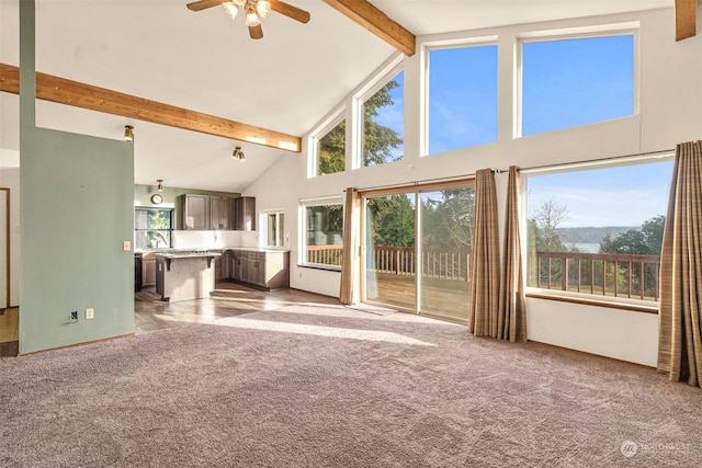 unfurnished living room featuring ceiling fan, sink, light colored carpet, beam ceiling, and high vaulted ceiling