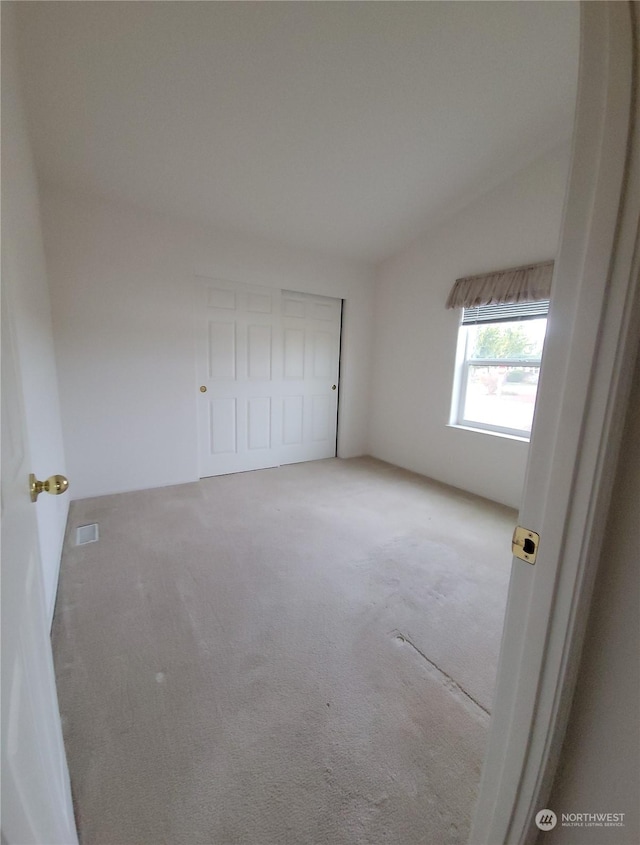 unfurnished bedroom with lofted ceiling and light colored carpet