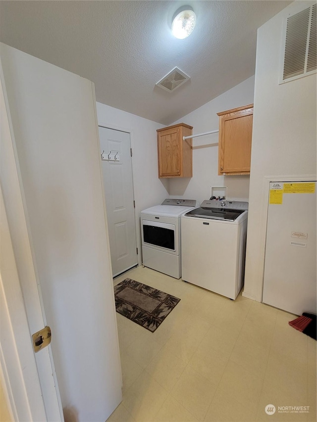 washroom featuring cabinets, a textured ceiling, and independent washer and dryer