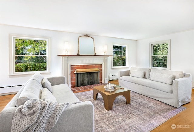 living room with a brick fireplace, wood-type flooring, and a baseboard radiator