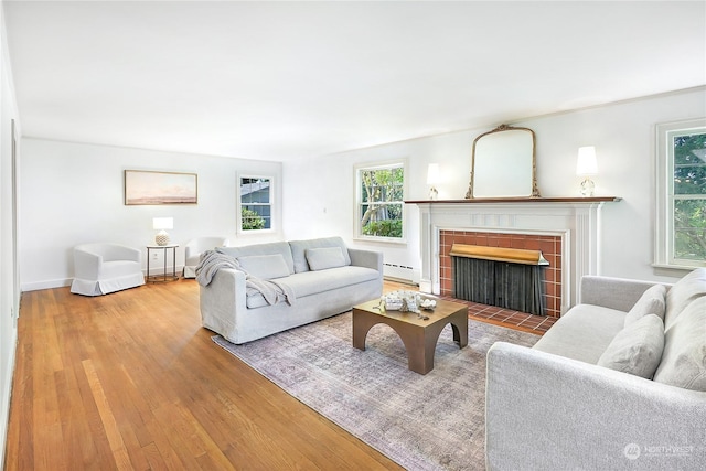 living room with a baseboard radiator, hardwood / wood-style floors, and a fireplace