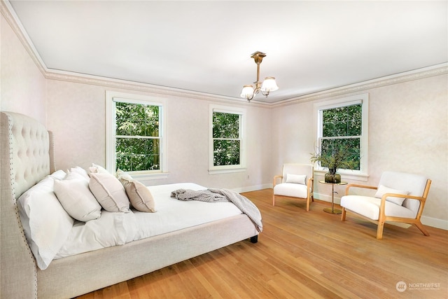 bedroom featuring wood-type flooring, ornamental molding, and a chandelier