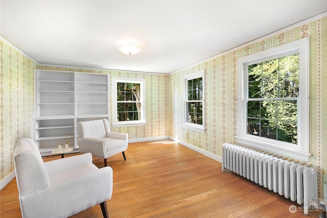 sitting room featuring radiator heating unit, ornamental molding, and light hardwood / wood-style floors