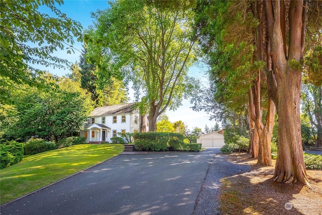 exterior space with a front yard, a garage, and an outbuilding