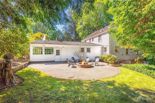 rear view of property with a lawn, a fire pit, and a patio