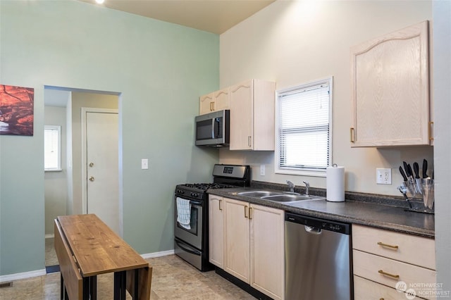 kitchen with stainless steel appliances, light brown cabinets, and sink