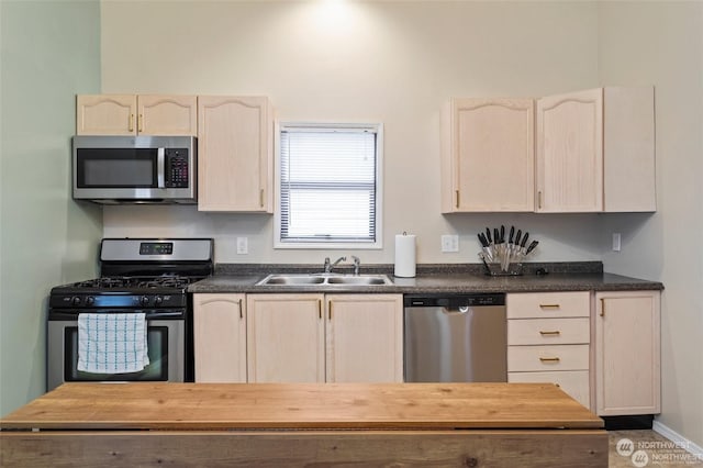 kitchen with appliances with stainless steel finishes, sink, and light brown cabinets