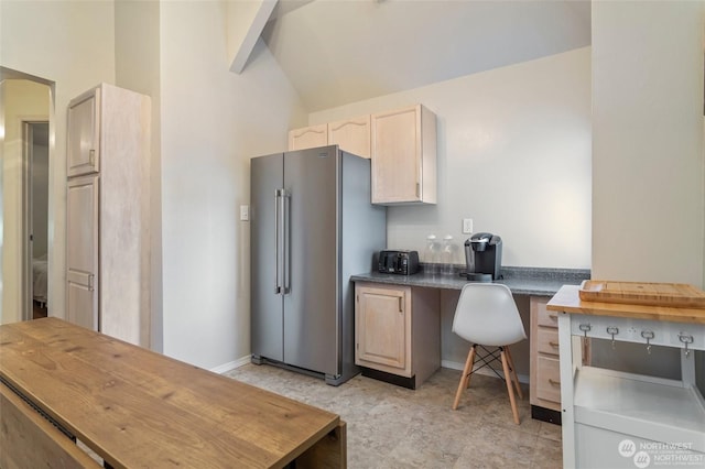 kitchen featuring high quality fridge, light brown cabinets, lofted ceiling with beams, and built in desk