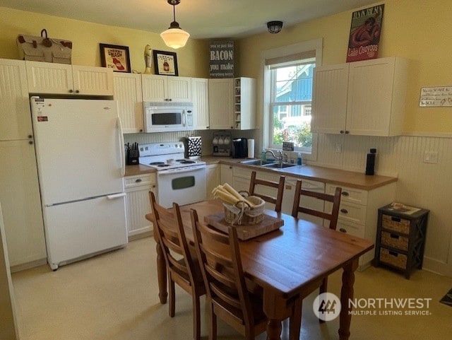 kitchen with white cabinetry, hanging light fixtures, white appliances, and sink