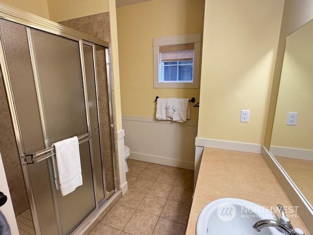 bathroom featuring tile patterned flooring, sink, toilet, and walk in shower