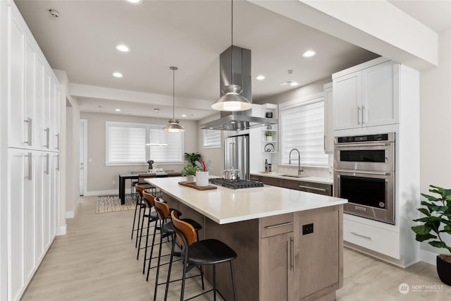 kitchen featuring pendant lighting, a center island, white cabinetry, stainless steel appliances, and sink