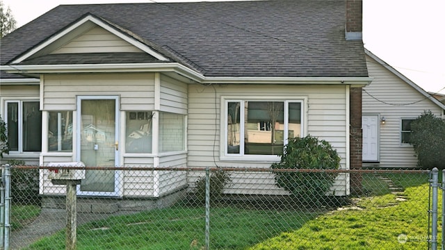 view of front of house featuring a chimney, roof with shingles, fence private yard, and a front lawn