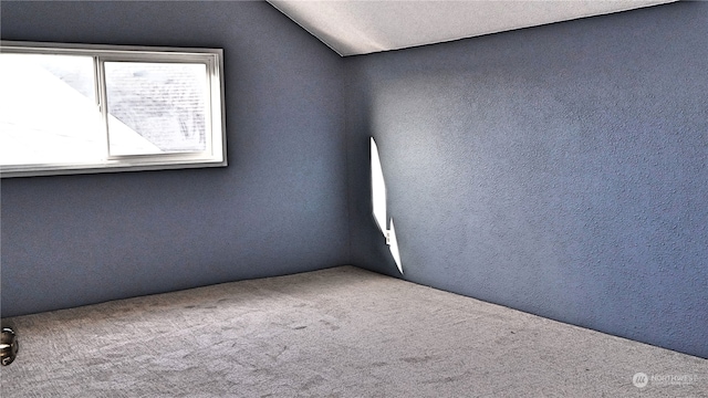 carpeted spare room with lofted ceiling