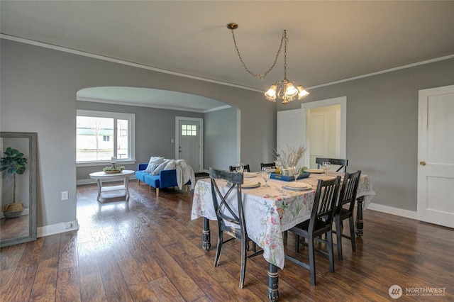 dining area with baseboards, arched walkways, ornamental molding, dark wood-type flooring, and a chandelier