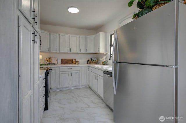 kitchen featuring light countertops, stainless steel appliances, marble finish floor, white cabinetry, and a sink